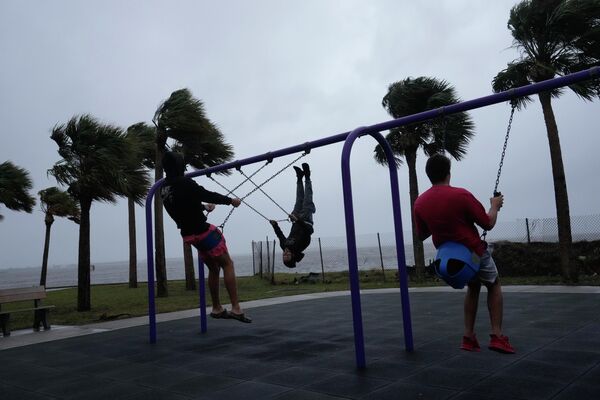 Young men brave strong winds and intermittent rain to play on a swing set along Jensen Beach Causeway, as conditions deteriorate with the approach of Hurricane Nicole, Wednesday, Nov. 9, 2022. - Sputnik International