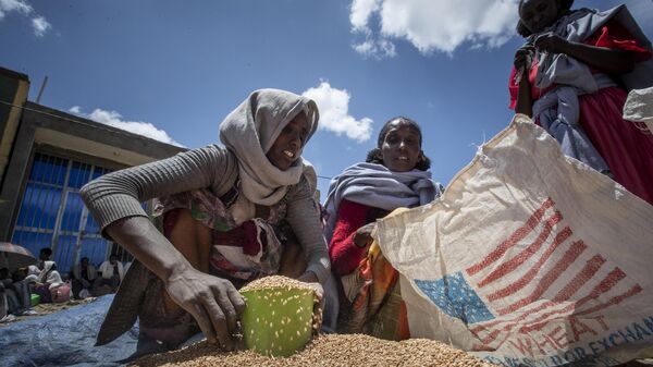  In this Saturday, May 8, 2021 file photo, an Ethiopian woman scoops up portions of wheat to be allocated to each waiting family after it was distributed by the Relief Society of Tigray in the town of Agula, in the Tigray region of northern Ethiopia. - Sputnik International