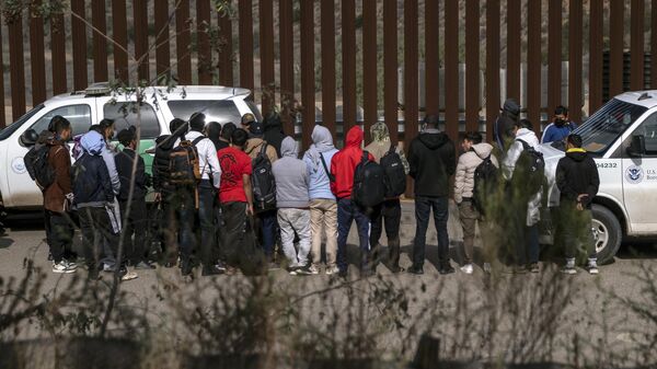 A border patrol agent talks to a group of migrants before processing them after they crossed the US-Mexico border on November 11, 2022. - Sputnik International