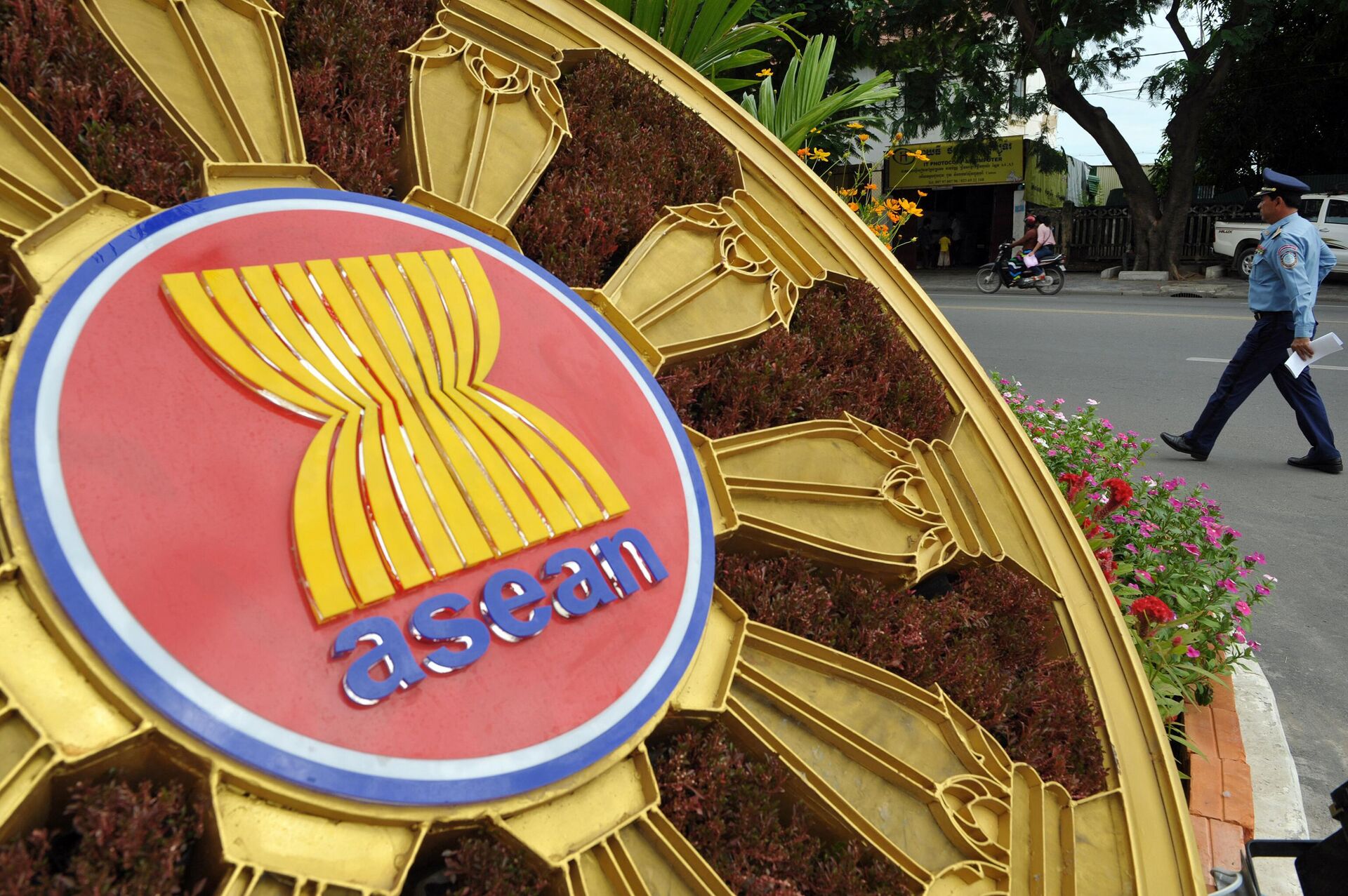 A Cambodian police officer (R) walks past the ASEAN logo in front of the Peace Palace during the 45th Association of Southeast Asian Nations (ASEAN) Foreign Ministers' Meeting (AMM) in Phnom Penh on July 8, 2012.  Efforts to ease tensions in the South China Sea will dominate this week's Asian security dialogue in Cambodia, analysts say, while the US will be at pains to stress it seeks cooperation, not rivalry, with China.  - Sputnik International, 1920, 23.11.2022