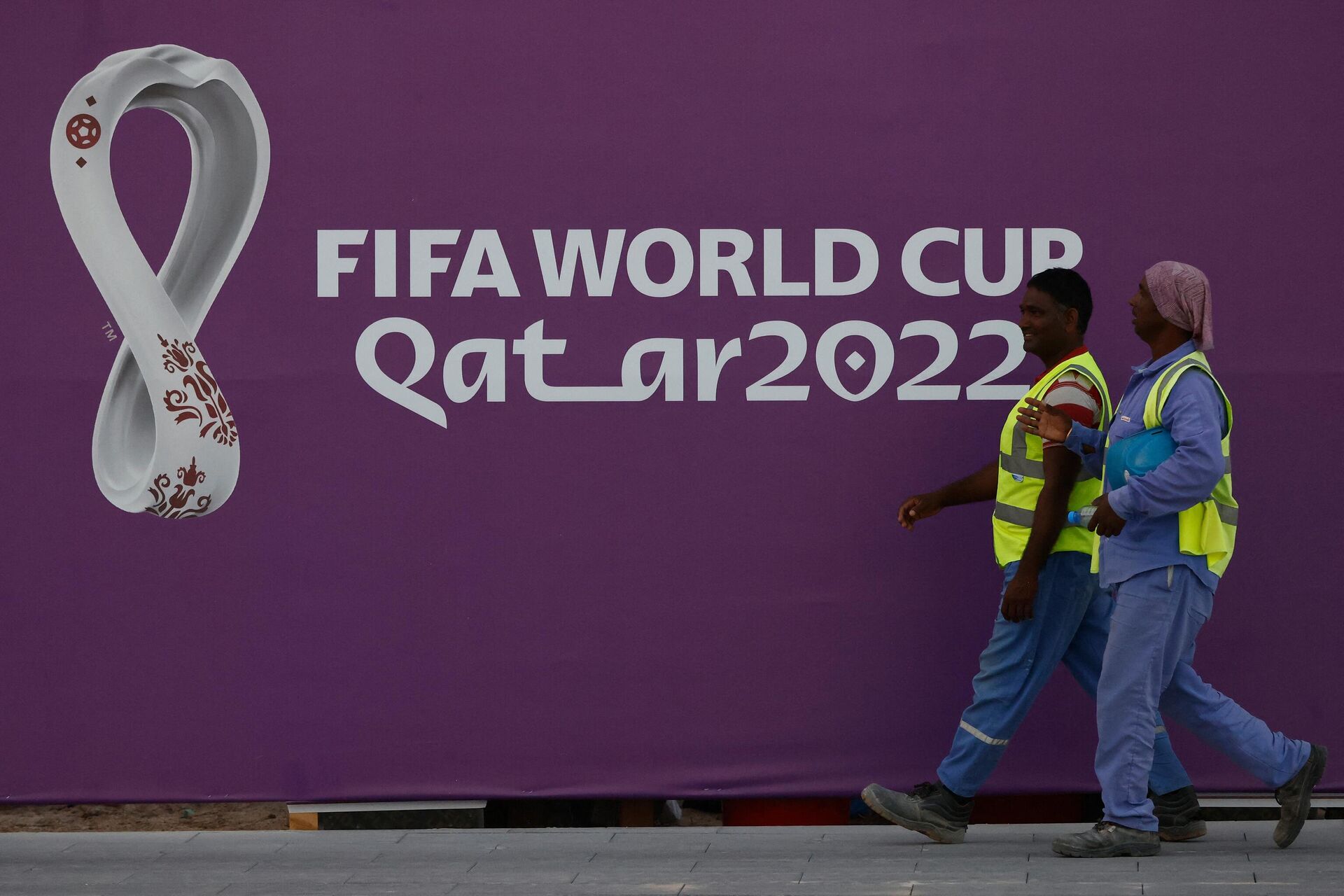 Workers walk past a FIFA World Cup sign in Doha on November 16, 2022, ahead of the Qatar 2022 World Cup football tournament.  - Sputnik International, 1920, 17.11.2022