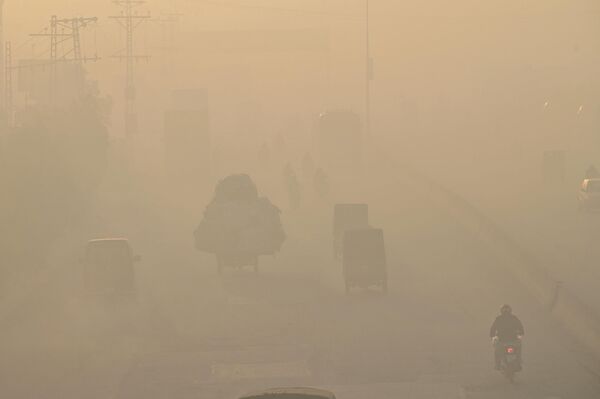 Commuters make their way along a street amid heavy smog in Lahore on November 18, 2022. - Sputnik International