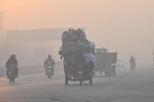 Commuters make their way along a street amid heavy smog in Lahore on November 18, 2022. - Sputnik International