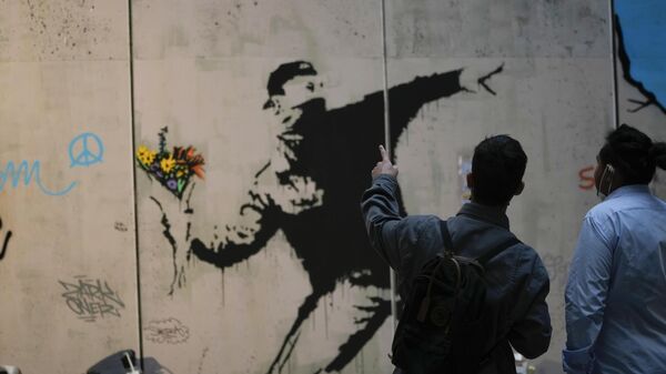Visitors walk past Flower Thrower, a reproduction of a mural by British artist Banksy, during the unveiling of the The World of Banksy, The Immersive Experience exhibition, in Milan, Italy, Thursday, Dec. 2, 2021. - Sputnik International