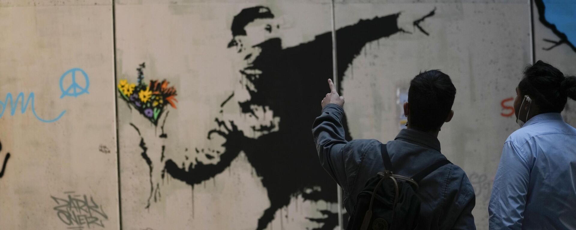 Visitors walk past Flower Thrower, a reproduction of a mural by British artist Banksy, during the unveiling of the The World of Banksy, The Immersive Experience exhibition, in Milan, Italy, Thursday, Dec. 2, 2021. - Sputnik International, 1920, 19.11.2022
