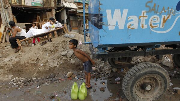A small boy takes a bath at a community water tank provided by the city municipality as a man relaxes on a charpoy as the day ends in New Delhi, India, Friday, June 24, 2011.  - Sputnik International