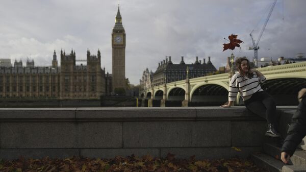 A woman poses for a photograph in front of the Houses of Parliament - Sputnik International