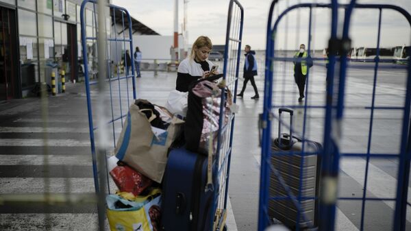 A woman from Ukraine checks her mobile as she arrives with her belongings at the temporary refugee shelter.  - Sputnik International