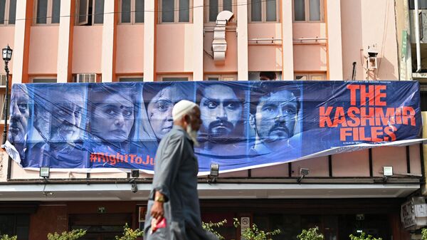 A man walks past a banner of Bollywood movie 'The Kashmir Files' installed outside a cinema hall in the old quarters of Delhi on March 21, 2022. - Sputnik International