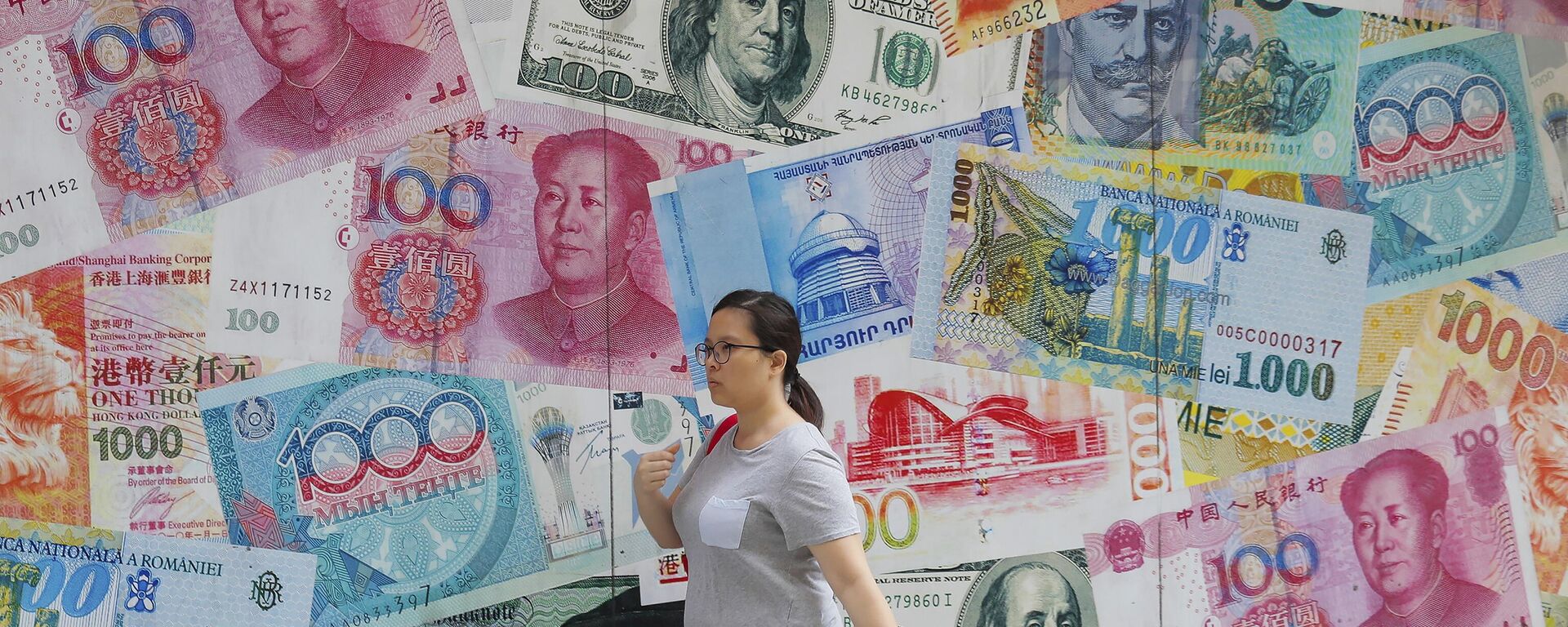  A woman walks by a money exchange shop decorated with different countries currency banknotes at Central, a business district in Hong Kong, Aug. 6, 2019. - Sputnik International, 1920, 24.08.2023