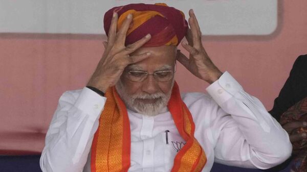 Indian Prime Minister Narendra Modi removes a turban presented to him during a public meeting ahead of the upcoming Gujarat state assembly elections in Mehsana, India, Wednesday, Nov. 23, 2022. - Sputnik International