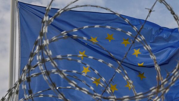 A European Union flag waves behind barbwires at the new closed center for migrants in the Greek island of Kos on November 27, 2021. - Sputnik International