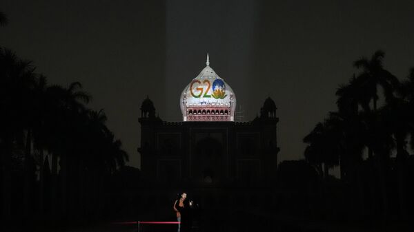 A television correspondent reports standing in front of Safdarjung's tomb lit up with the G20 logo, in New Delhi, Thursday, Dec. 1, 2022. - Sputnik International