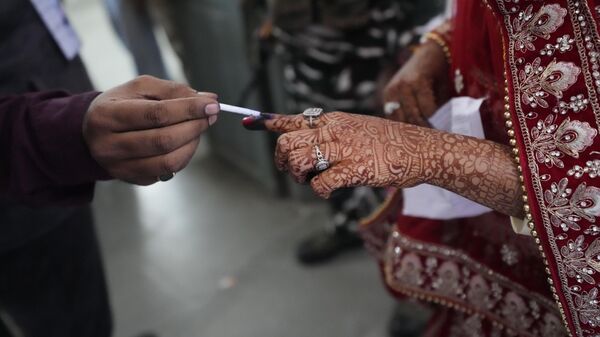 A election officer applies indelible ink mark on the index finger of a bride during the second phase of Gujarat state legislature elections in Ahmedabad, India, Monday, Dec. 5, 2022. - Sputnik International
