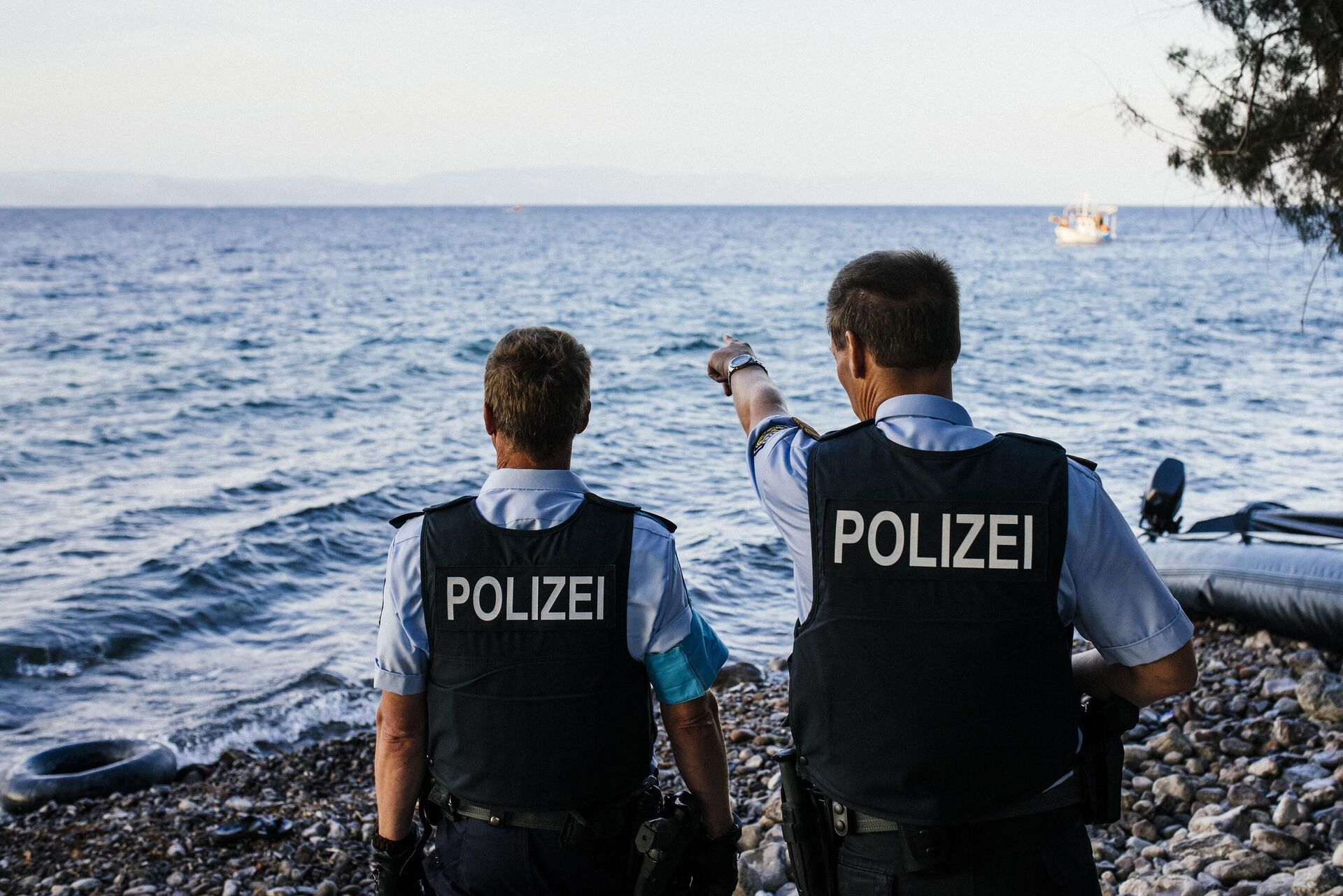 German police officers, representatives of the EU's border management agency Frontex, on the Greek island of Lesbos, look at a dinghy with migrants crossing the Aegean sea from Turkey, on October 17, 2015. - Sputnik International, 1920, 06.12.2022