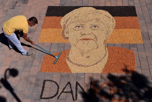 Kosovo artist Alkent Pozhegu works on the final touches of an image made with grain and seed depicting the portrait of former-German Chancellor Angela Merkel in the town of Gjakova on September 26, 2021. - Sputnik International