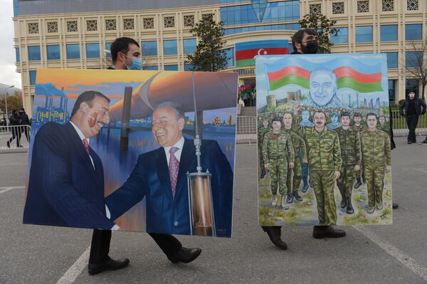Men carry posters of Azerbaijani President Ilham Aliyev down a Baku street after a military parade. - Sputnik International