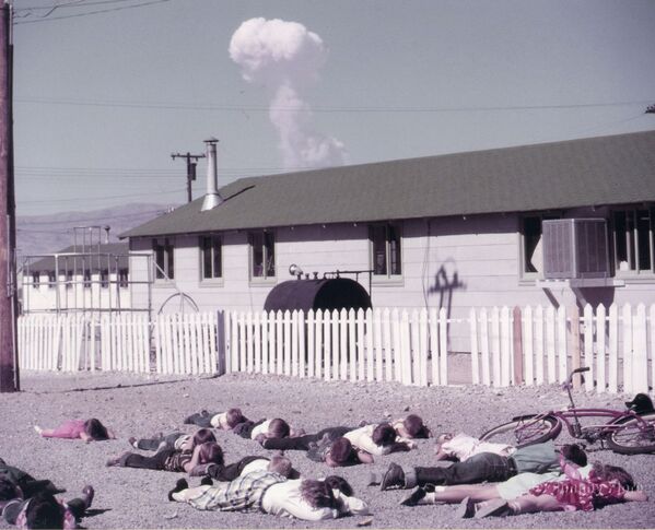 Students practice &quot;duck and cover&quot; personal protection measures against the backdrop of a real atomic bomb explosion. The photo was taken in Indian Springs, Nevada, 40 kilometers from the epicenter of a 31-kiloton aerial atomic bomb explosion. Date and time: April 22, 1952, 09:30. - Sputnik International