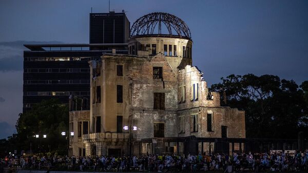 People gather beside the Hiroshima Prefectural Industrial Promotion Hall, commonly known as the atomic bomb dome, to watch paper lanterns being released on the Motoyasu River to mark the 77th anniversary of the world's first atomic bomb attack in Hiroshima on August 6, 2022. - Sputnik International