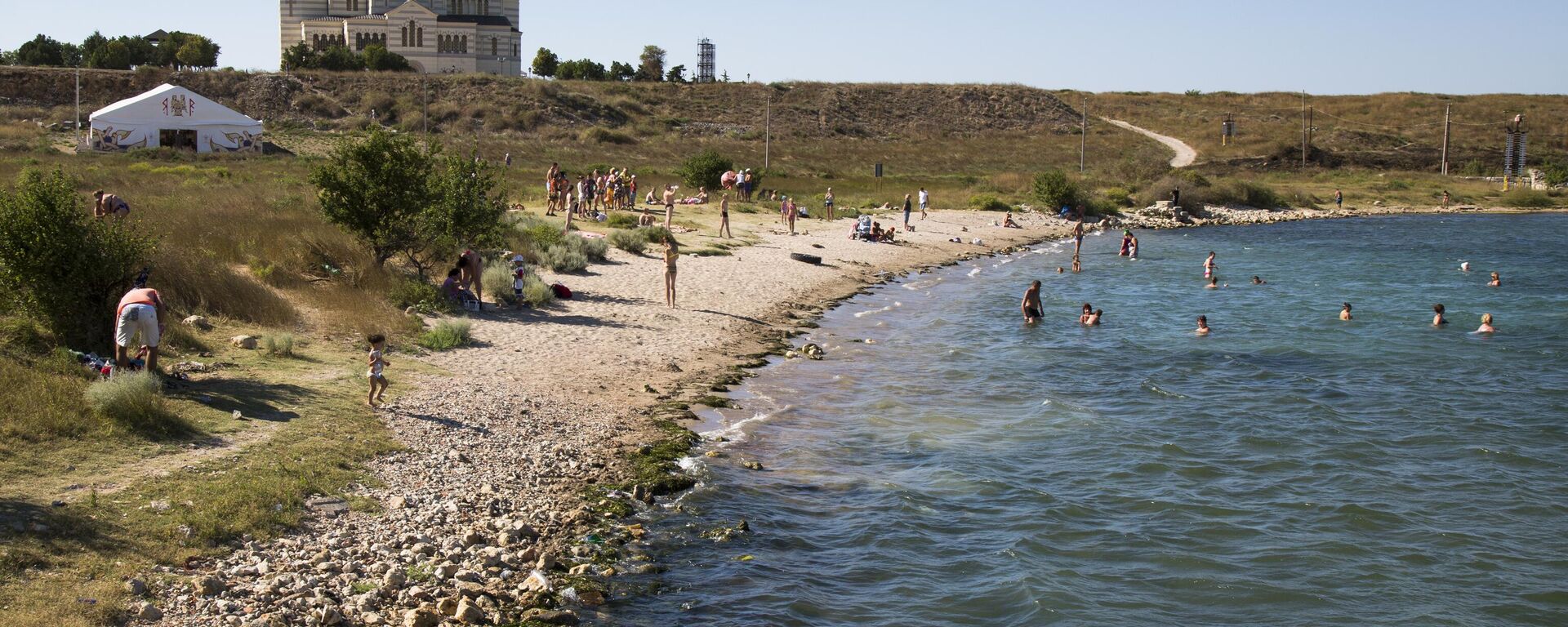 In this photo taken on Friday, Aug.  7, 2015, people gather at the beach area of the Black Sea, near to the area that was the ancient Greek colony of Chersonesus, and with the St. Vladimir's Cathedral in the background, just outside Sevastopol, the main port city in Crimea, the Black Sea Peninsula .  - Sputnik International, 1920, 23.06.2024