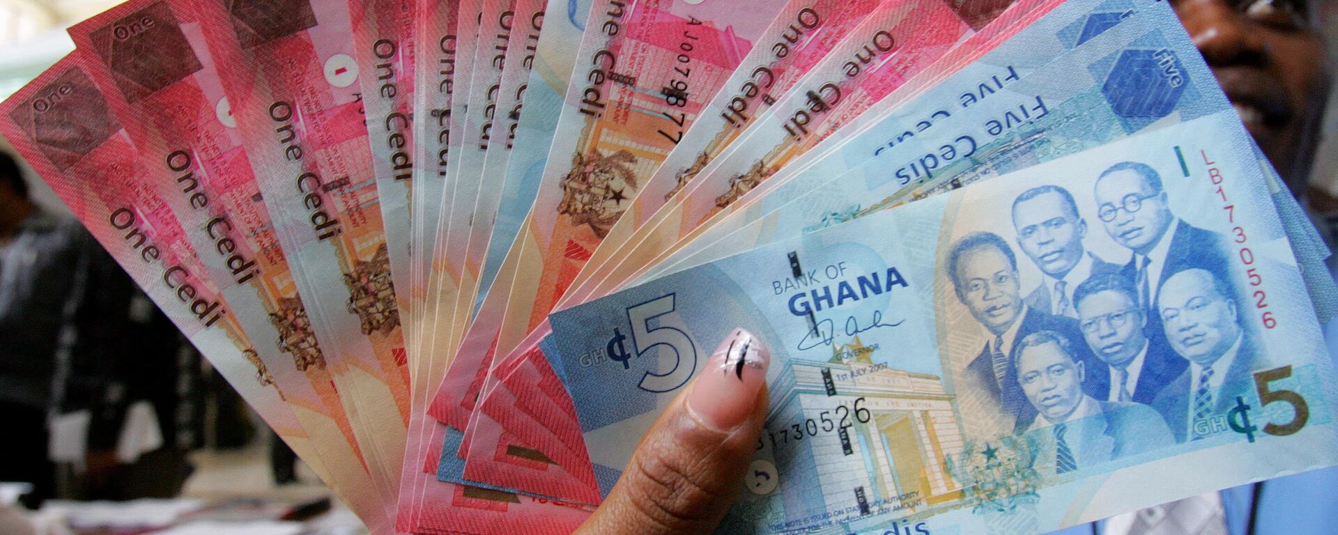 A woman holds 03 July 2007 in Accra a wad new currency, the new cedi, that Ghana put in circulation that day, although the old money will still be valid until the end of the year.  - Sputnik International, 1920, 10.12.2022