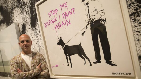 Curator Steve Lazarides poses for a portrait next to at art work by British artist Banksy. - Sputnik International