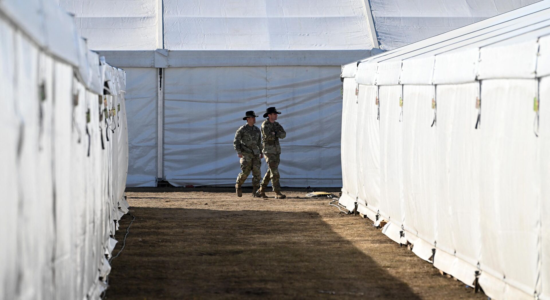 US soldiers walk between tents at the United States Army military training base in Grafenwoehr, southern Germany, on March 11, 2022. - Sputnik International, 1920, 14.12.2022