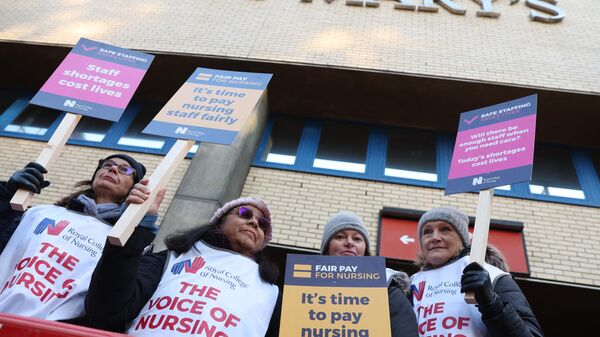 Healthcare workers hold placards at a picket line outside St Mary's Hospital in west London on December 15, 2022. - Sputnik International