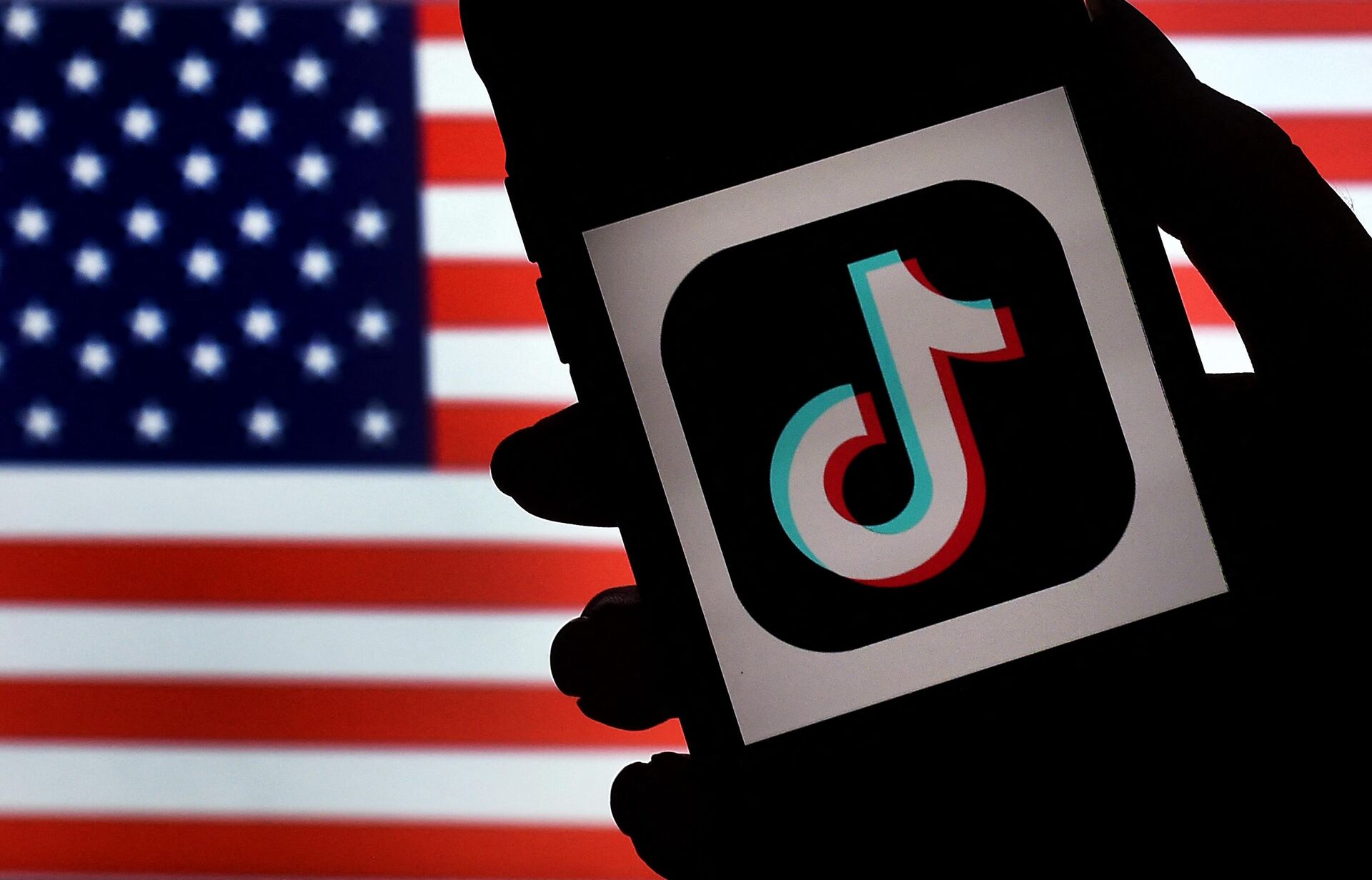 The social media application logo, TikTok is displayed on the screen of an iPhone on an American flag background.  - Sputnik International, 1920, 20.12.2022