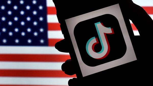 The social media application logo, TikTok is displayed on the screen of an iPhone on an American flag background.  - Sputnik International