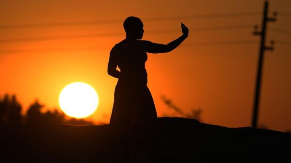 A woman takes a selfie with her phone at sunset on the outskirts of Harare, Tuesday, May, 24, 2022. Zimbabwe joins the rest of Africa in commemorating Africa Day, the commemoration of the foundation of the Organisation of African Unity on 25 May 1963. - Sputnik International
