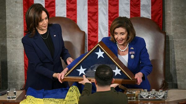 US House Speaker Nancy Pelosi (D-CA) (R) and US Vice President Kamala Harris (L) present Ukraine's President Volodymyr Zelensky an American flag after receiving a Ukrainian national flag from him following his address to the US Congress at the US Capitol in Washington, DC on December 21, 2022. - Sputnik International