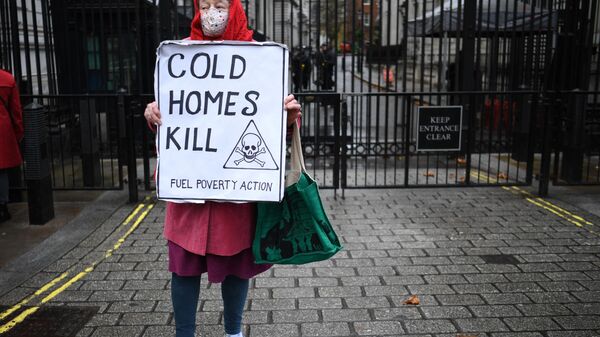 A protestor holds a placard highlighting the excess winter deaths caused by fuel poverty - Sputnik International