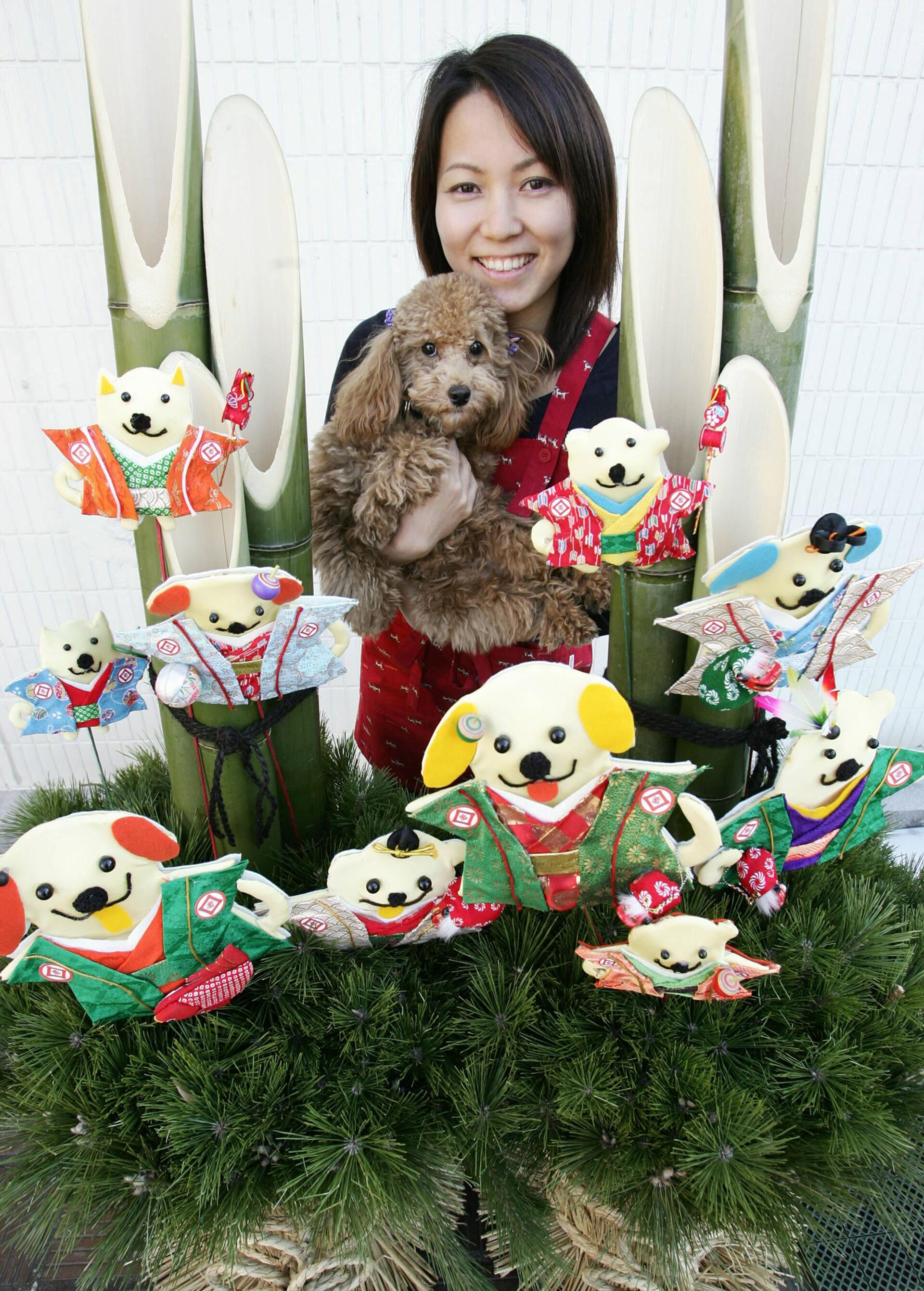 Hiromi Otsuka, employee of a pet shop at Ginza Matsuzakaya department store, holds a poodle in front of a pair of kadomatsu, or pine branches with dog-shaped decoration in Tokyo, 31 December 2005. - Sputnik International, 1920, 24.12.2022