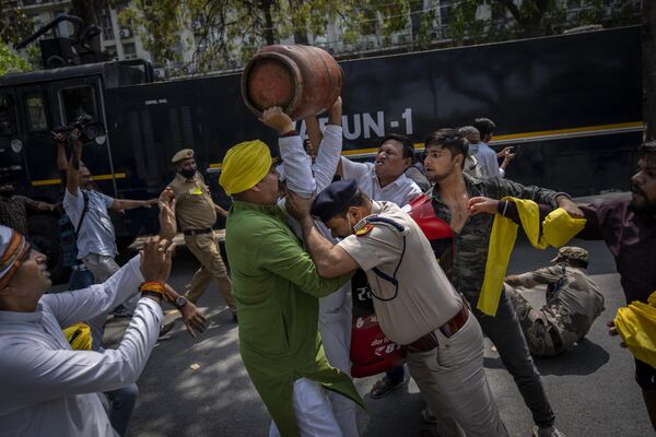 A Delhi police officer tries to stop an opposition Congress Party supporter as he raises an empty Liquefied Petroleum Gas (LPG) cylinder over his head during a protest against rising inflation and price hikes of essential commodities in Delhi, India, Wednesday, March 23, 2022. - Sputnik International