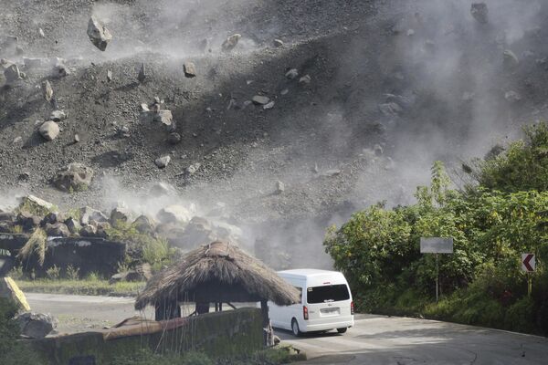 Boulders fall as a vehicle negotiates a road during an earthquake in Bauko, Mountain Province, Philippines on Wednesday July 27, 2022. A strong earthquake left some people dead and injured dozens in the northern Philippines where the temblor set off small landslides and damaged buildings and churches and prompted terrified crowds and hospital patients in the capital to rush outdoors. One passenger was injured after a boulder hit the vehicle. - Sputnik International