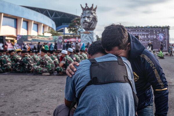 Indonesian army soldiers and civilians pay their respects for victims of the stampede at Kanjuruhan stadium in Malang, East Java on October 4, 2022. Elite Indonesian police officers were under investigation on October 4 over a stadium stampede that killed 125 people including dozens of children in one of the deadliest disasters in football history. - Sputnik International