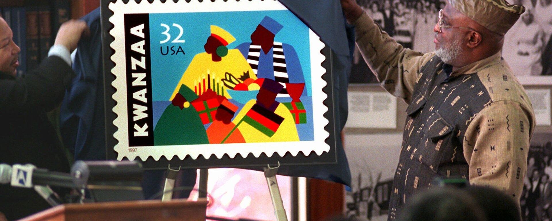 Harold Anderson, left, joins Jose Ferrer, right, chairman of the Kwanzaa Holiday Foundation, to unveil the new Kwanzaa postage stamp at the Shomburg Center for Research in Black Culture in Harlem, New York, Wednesday, Nov. 12, 1997.  Ferrer, who is from the Bronx borough of New York, led efforts to create the stamp and says this will make America aknowledge the importance of this great celebration and the affirmation of our culture.  The commemorative Holiday Celebration stamp series pays tribute to the African-American family and community.  - Sputnik International, 1920, 26.12.2022