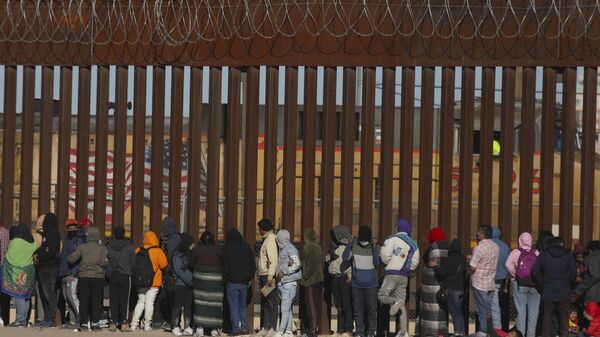 Migrants queue at the border wall to be received by Border Patrol agents after crossing the Rio Bravo river (or Rio Grande river, as it is called in the US) from Ciudad Juarez, Chihuahua state, Mexico to El Paso, Texas, US on December 21, 2022 - Sputnik International