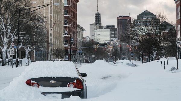 An abandoned vehicle is left under heavy snow along a street in Buffalo, New York, on December 25, 2022. - Sputnik International