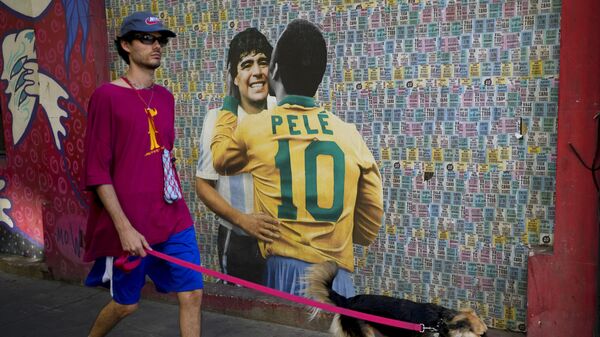 A man walks his dog walk past a mural showing Brazilian soccer legend Pele and Argentina late soccer star Diego Armando Maradona in Buenos Aires, Argentina, Thursday, Dec. 29, 2022. Pele, who won a record three World Cups has died at the age of 82. - Sputnik International