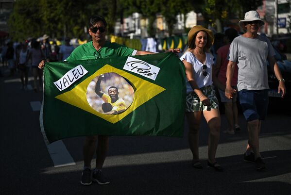 A mourner displays a Brazilian flag with the face of Brazilian football legend Pele outside the Urbano Caldeira stadium where a wake is being held in his honor, in Santos, Sao Paulo, Brazil, on January 2, 2023.  - Sputnik International