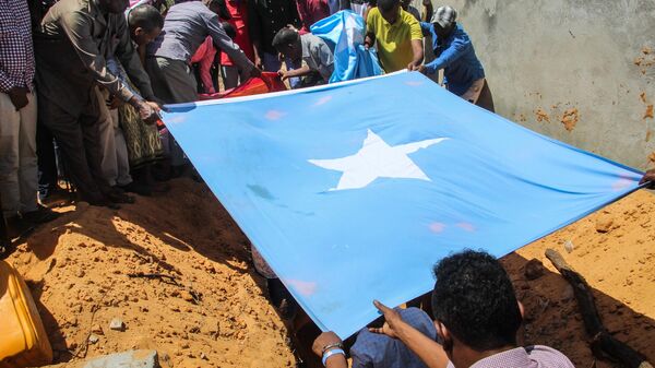 Family members hold the naitonal flag as they bury the body of Abdiaziz Mohamud Guled, the director of government-owned Radio Mogadishu, in Mogadishu, Somalia, on November 21, 2021. - Sputnik International