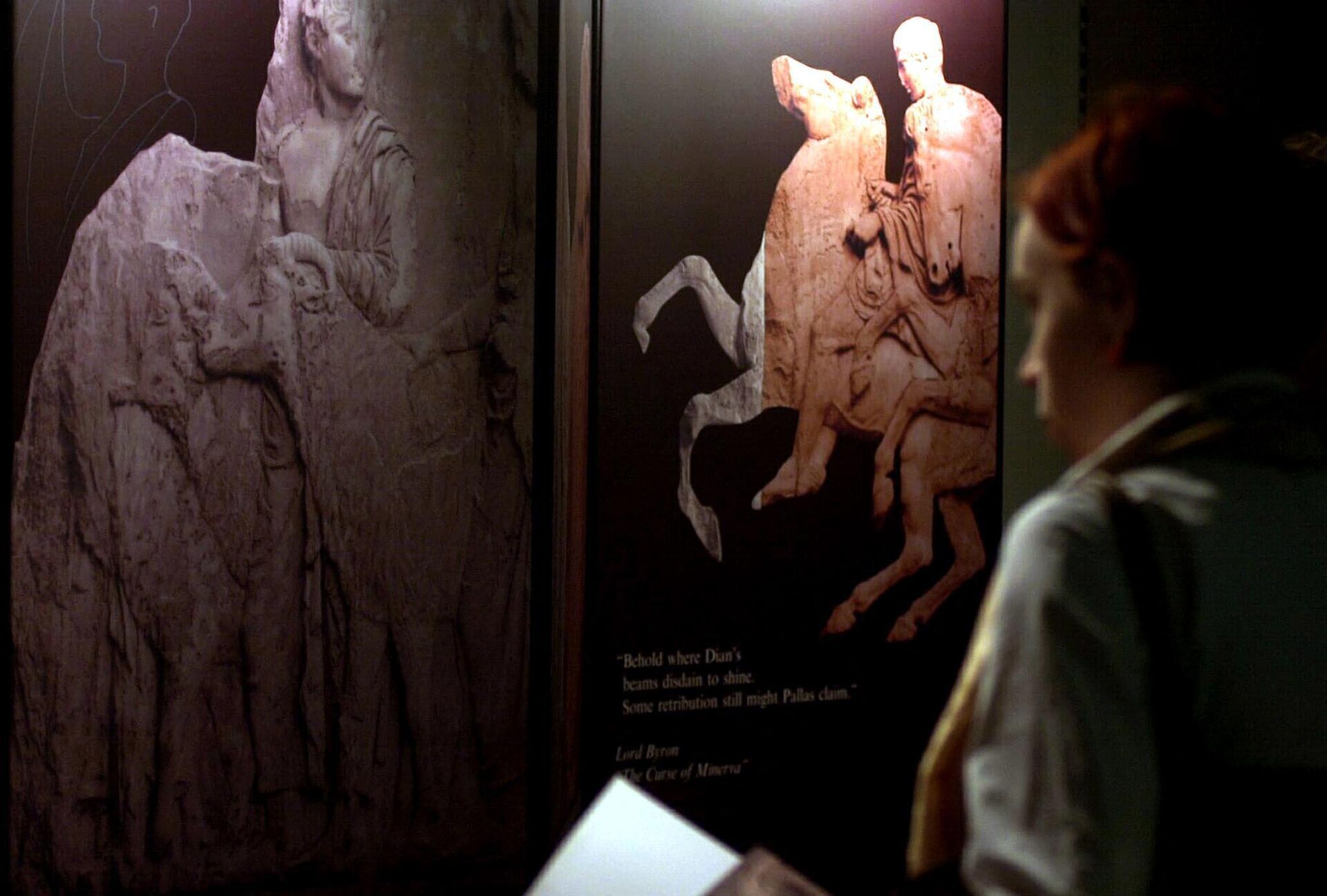 A woman looks at some of the so-called Elgin marbles (L) while a show of computer simulated images shows how the new Acropolis museum in Greece will be with the reunited Parthenon Marbles 27 January 2003, at Portcullis house, Westminster, in London.  - Sputnik International, 1920, 05.01.2023