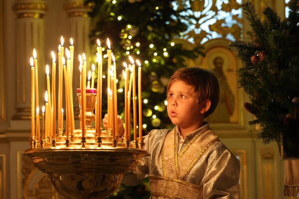 A boy lights a candle during Orthodox Christmas Eve celebrations at the Russian Orthodox Church in the Gulf emirate of Sharjah on January 6. (Photo by Giuseppe CACACE / AFP) - Sputnik International