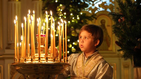 A boy lights a candle during Orthodox Christmas Eve celebrations at the Russian Orthodox Church in the Gulf emirate of Sharjah on January 6, 2023.  - Sputnik International