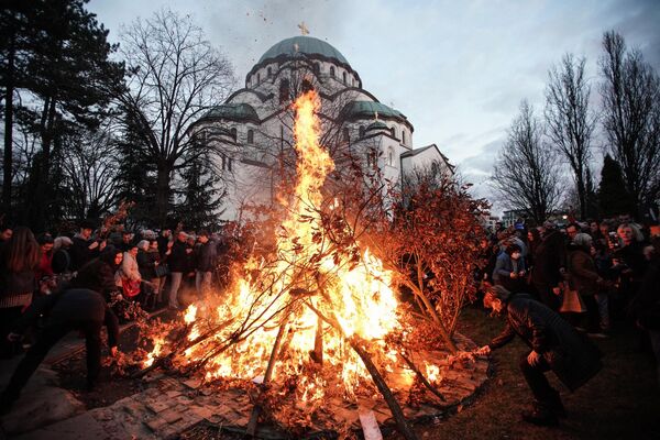 People attend the annual ceremony of lighting a bonfire of dried oak branches, the Yule log symbol for the Orthodox Christmas Eve, according to the Julian calendar, at the Church of Saint Sava in Belgrade on January 6. (Photo by OLIVER BUNIC / AFP) - Sputnik International