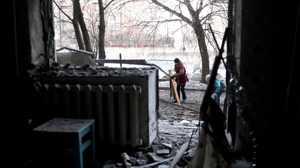 Local women clean up outside a house that was damaged by a Ukrainian night shelling in Gorlovka. - Sputnik International
