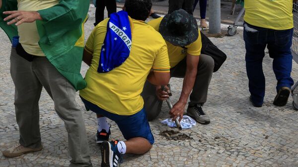 Supporters of Brazilian former President Jair Bolsonaro damage the sidewalk to obtain stones during clashes with riot police outside Planalto Presidential Palace - Sputnik International