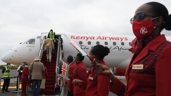Kenya Airways cabin crew members (R), waive flags as they usher passengers at the Jomo Kenyatta International Airport (JKIA), after the official launch on resumption of local flights in Nairobi, on July 15, 2020.  - Sputnik International